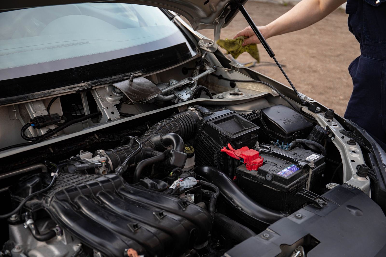 A car with its hood open, engine bay and battery in view