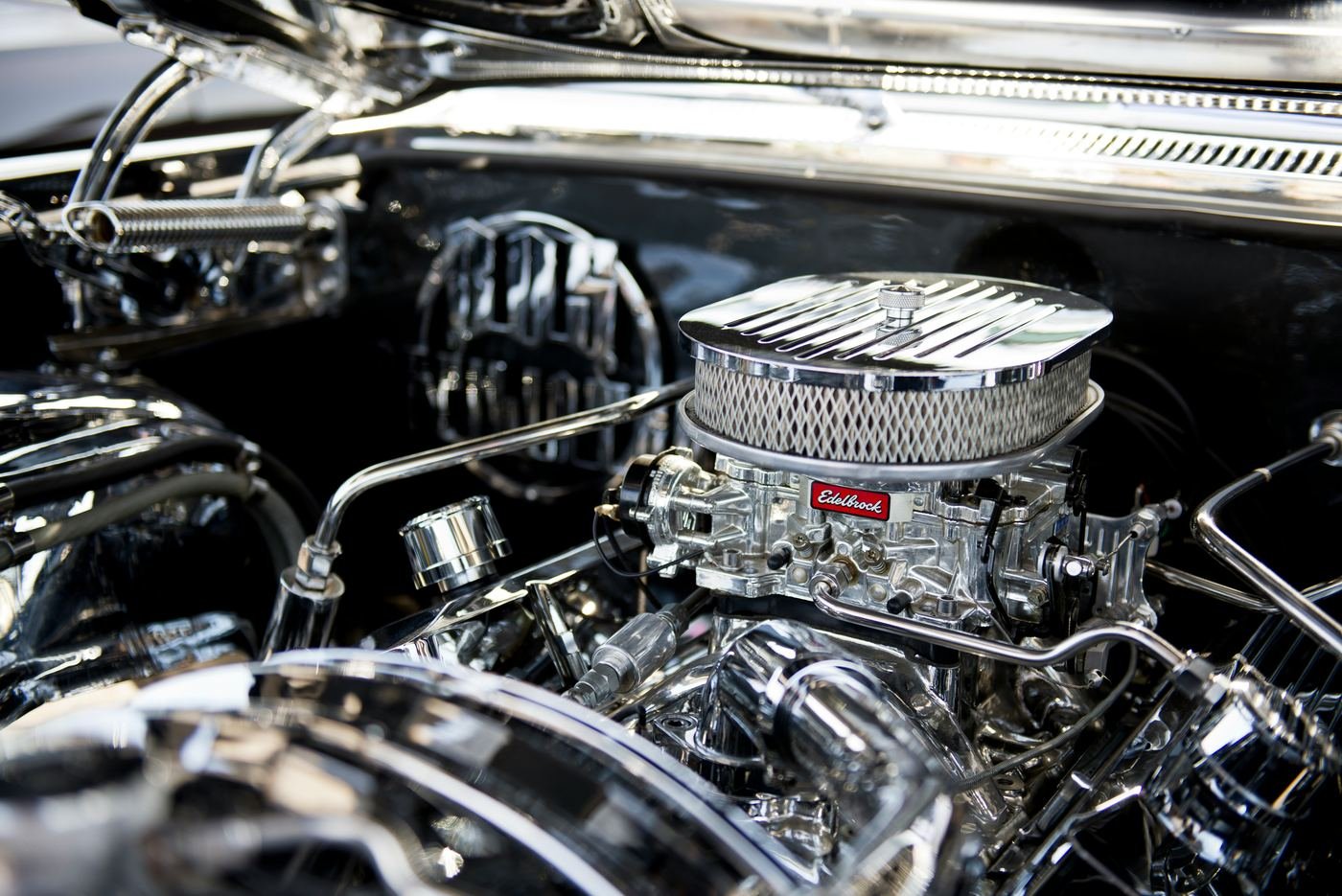 A chrome air cleaner and polished engine parts in a classic car’s engine bay
