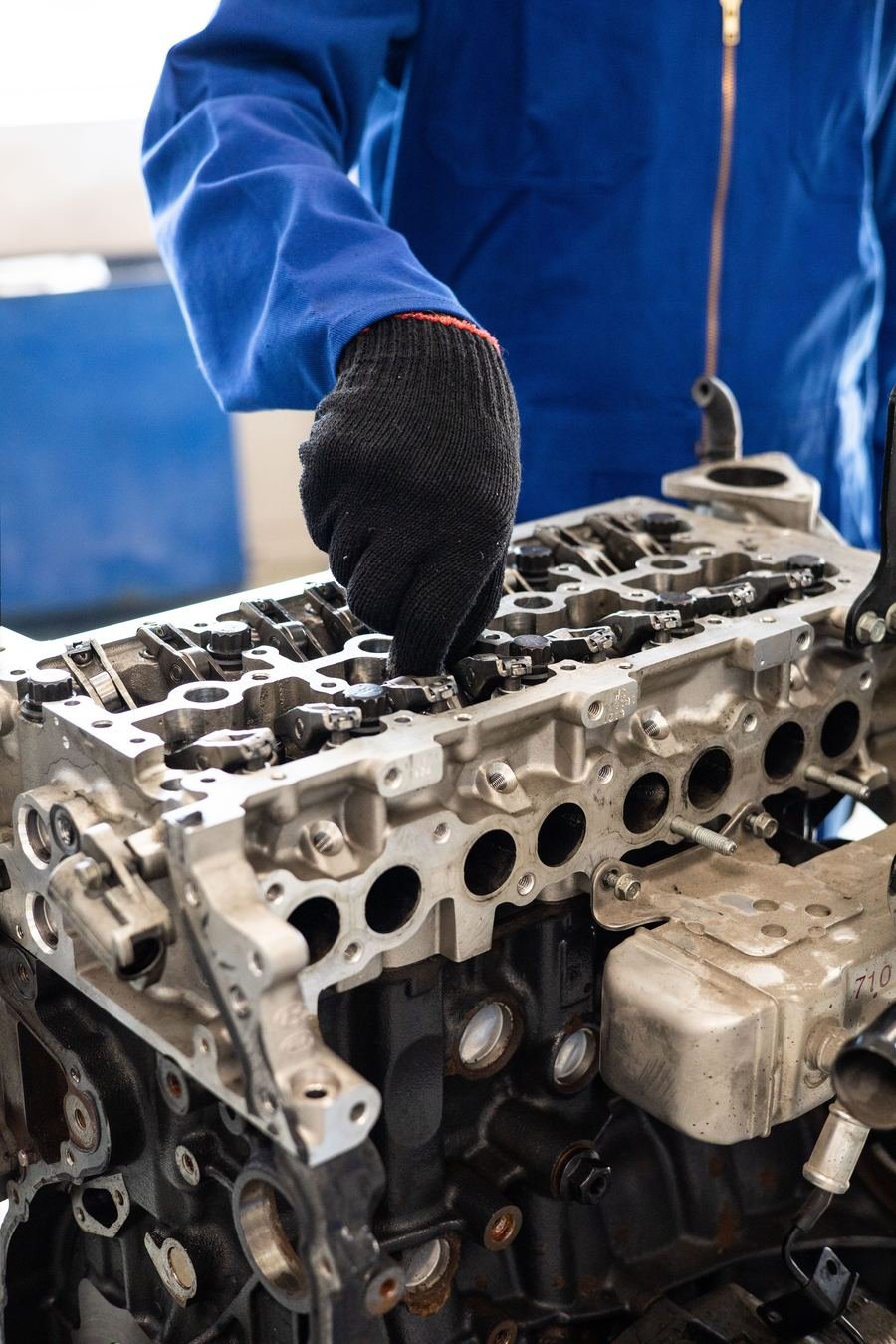 A mechanic in gloves working on a bare engine block on a stand