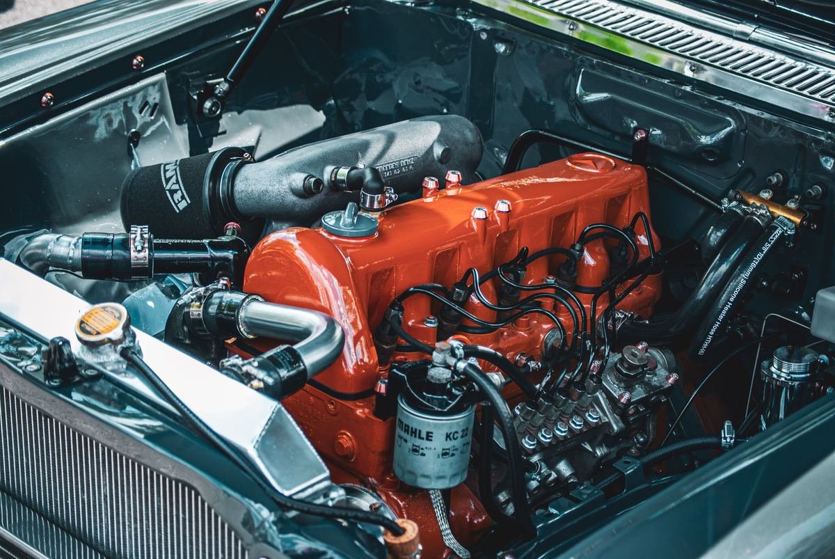 An engine with an orange-painted block and braided hoses